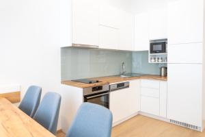 维也纳Modern 3 room apartment in a prime location的厨房配有白色橱柜、蓝色椅子和桌子