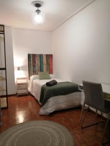 毕尔巴鄂Piso luminoso, amplio y tranquilo en Casco Viejo的一间卧室配有一张床、一张桌子和一把椅子