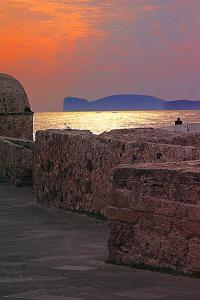 阿尔盖罗Home Feeling Mascagni - Bilocale的日落时分在海边的石墙
