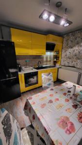 肯普隆格Safta Apartaments的一个带两张桌子的厨房和一个带黄色橱柜的厨房