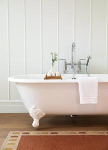汉普顿贝斯Canoe Place Inn & Cottages的浴室内设有带水槽的白色浴缸