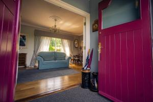 阿比菲尔Park Lodge Bed and Breakfast的一道红色的门通向一个带蓝色沙发的客厅