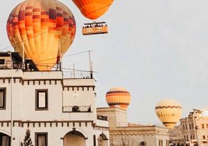 格雷梅Osmanli Cappadocia Hotel的一组热气球飞越一座建筑物