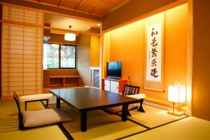 京都Kyoto Arashiyama Onsen Ryokan Togetsutei的配有桌椅和电视的客房