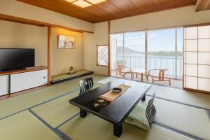 宫津市天野桥立日式旅馆的客厅配有电视和桌椅