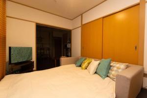 东京Grace Heiwajima的卧室配有一张带彩色枕头的大型白色床。