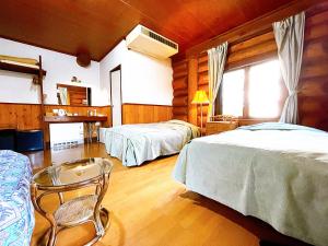 白马村Hakuba Pension & Log Hotel Meteor的一间卧室配有两张床和椅子