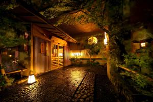 京都Kyoto Arashiyama Onsen Ryokan Togetsutei的一座带庭院的建筑,晚上有灯光