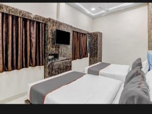 加姆布Hotel Bhavya Residency的一间卧室设有两张床,墙上配有电视。