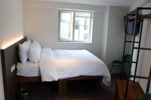 首尔H HOSTEL Itaewon的一间卧室配有一张带白色床单的床和一扇窗户。