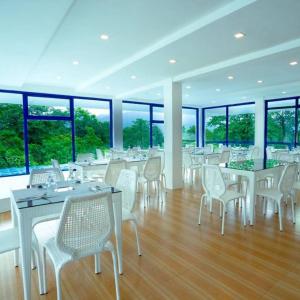 科隆Ruhe Suites Coron的餐厅设有白色的桌椅和窗户。