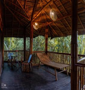 瓦亚纳德Uravu Bamboo Grove Resort的门廊配有吊床和桌椅