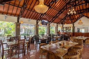 NegaraJimbarwana Hotel的一间带木桌椅的餐厅和一间酒吧