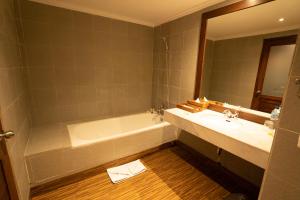 罗威那New Sunari Lovina Beach Resort的带浴缸、水槽和镜子的浴室