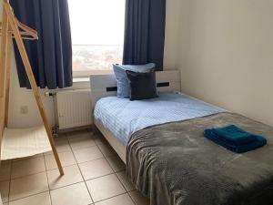 海边的艾格蒙特亚特兰蒂斯公寓的一间卧室配有一张带蓝色床单的床和一扇窗户。