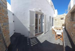 伊奥斯乔拉Deja vu Ευχάριστο σπίτι στο κέντρο του νησιού ΊΟΥ的白色的建筑,设有门和桌椅