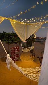 Muntarib瓦希巴贝都因乡间露营地的海滩上的吊床,配有灯和椅子