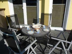 伯尔格伦德-雷特维施Appartement Sundevit的阳台上的桌子上放有杯子和碟子