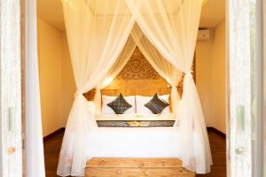 乌布Ubud Inn Cottage by Prasi的卧室配有带白色窗帘的天蓬床