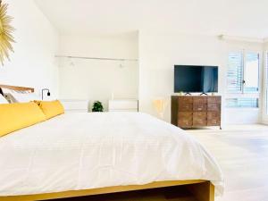 卢加诺Casa Vitus的白色卧室设有一张大床和电视。