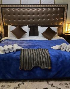 梅尔祖卡Luxury Desert Camp的一张带蓝色毯子和枕头的大床