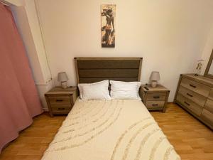 布加勒斯特National Arena Mega Mall Elana apartment的一间卧室配有一张带2个床头柜和2张桌子的床