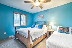 RoscommonHiggins Lake Retreat - Hike, Swim, Relax!的一间卧室设有蓝色的墙壁、一张床和吊扇。
