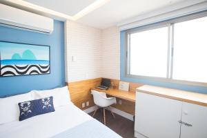 里约热内卢Barra da Tijuca de frente para o mar - 2 suítes até 6 pessoas em camas的一间卧室配有一张床、一张书桌和一个窗户。