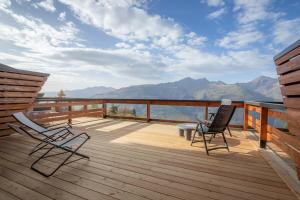 阿克 1600La Cachette, Friendly Hotel & Spa的木制甲板上设有两把椅子和一张桌子,享有山景。
