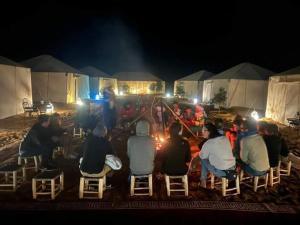 梅尔祖卡Ahlam Luxury Camp的一群人晚上坐在火炉旁