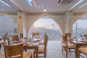 瓦迪穆萨Petra Elite Hotel的一间带桌椅的用餐室和大窗户