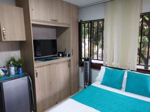 麦德林Apartaestudio Laureles - Viva Laureles的一间卧室配有一张带蓝色枕头的床和一台电视。