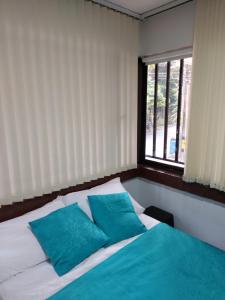 麦德林Apartaestudio Laureles - Viva Laureles的一间卧室配有一张带蓝色枕头的床和一扇窗户。