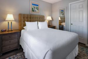 默特尔比奇Sea Mystique Resort的卧室配有一张白色大床和两盏灯。