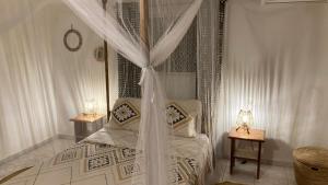 NdanganeVilla Kounzo的一间卧室配有一张带2个床头柜的天蓬床