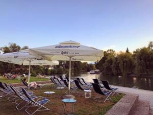 卢布尔雅那Villa Riverside的河边的一组椅子和遮阳伞