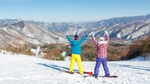 松本Kyukamura Norikura-Kogen的两个人站在雪覆盖的山顶上