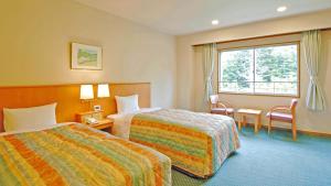 松本Kyukamura Norikura-Kogen的酒店客房设有两张床和窗户。