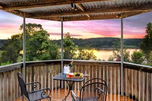 希尔斯维尔Sunset Cottage - Yarra Valley的湖景甲板上的桌椅