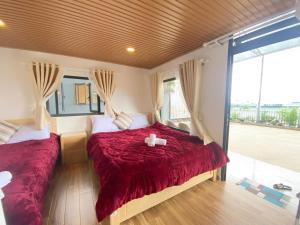 大叻Ngọc Nguyên Homestay的一间卧室设有两张带红色床单的床和窗户。