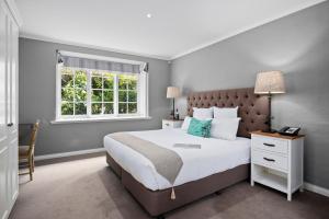 黑荒地Parklands Country Gardens & Lodges Blue Mountains的一间卧室设有一张大床和一个窗户。
