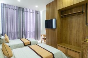 Buôn EnaoKhang Hy Hotel的酒店客房设有两张床和一台平面电视。