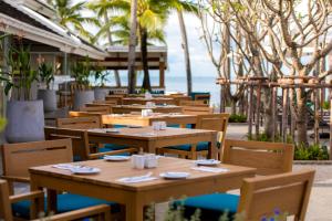 拉迈Outrigger Koh Samui Beach Resort - SHA Extra Plus的一间设有木桌和椅子的餐厅,享有海景