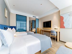 呼和浩特呼和浩特新城区摩尔城兰欧尚品酒店的卧室配有一张白色大床和一张书桌