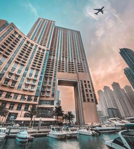 迪拜Address Dubai Marina Residences by Qstay的一座大建筑,上面有船在水里,还有飞机