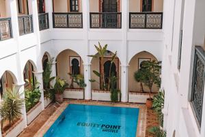 马拉喀什马拉喀什艾奎特酒店的一座带游泳池和植物的建筑的庭院