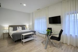 萨拉曼卡Inés Luna Suites的一间卧室配有一张床、一张桌子和一台电视。
