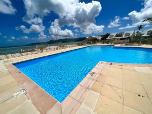 Baie NettleLa Plage Bleue feet in the water with swimming pool的海滩旁的大型蓝色游泳池