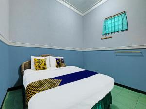 三宝垄SPOT ON 91912 Hotel Citra Dewi 2的一间卧室配有一张蓝色墙壁的床和一扇窗户