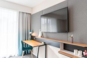 梅里尼亚克Holiday Inn - Bordeaux-Merignac, an IHG Hotel的酒店的客房,配有书桌和墙上的电视
